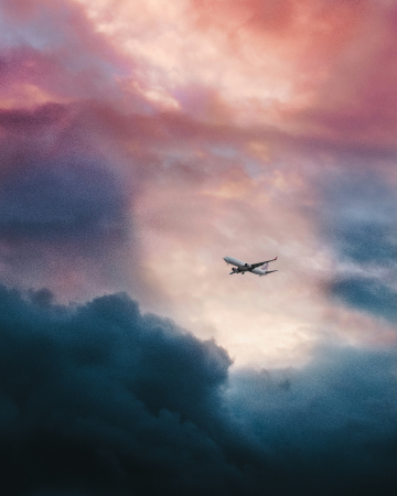 Airplane flying through vibrant clouds during a stunning sunset, symbolizing global travel and seamless connectivity.