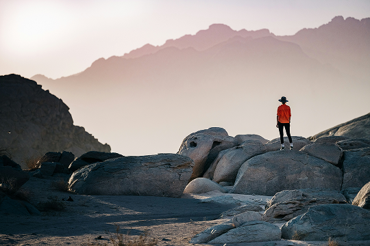 Traveler standing on rocky terrain, overlooking scenic mountains, highlighting the convenience of using a travel eSIM for seamless connectivity in remote locations.